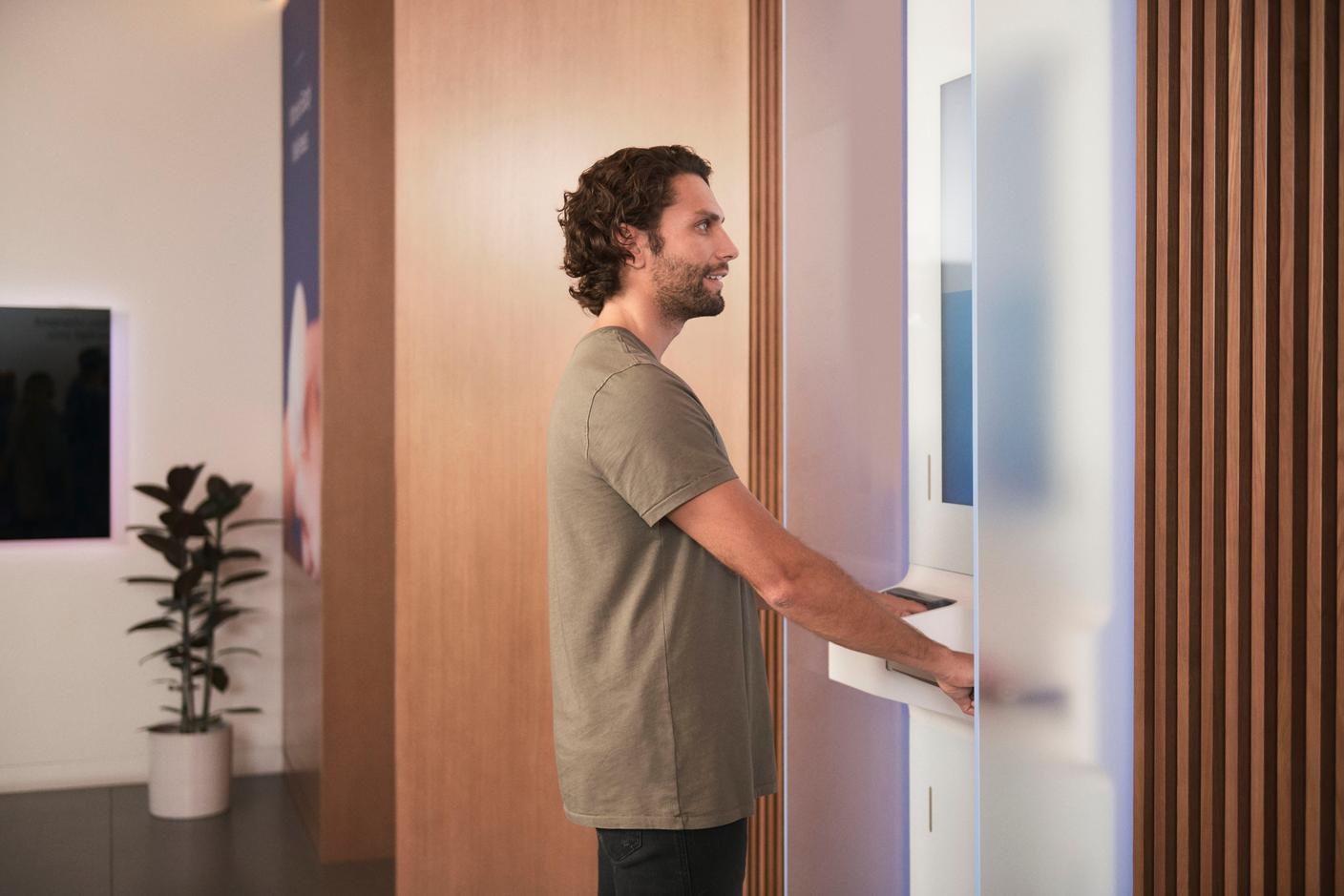 A side profile of a male Forward member on the body scanner with his hands in the sensors to detect his vitals.