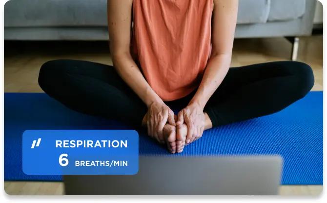 Young female sitting on a mat doing yoga in front of a laptop screen