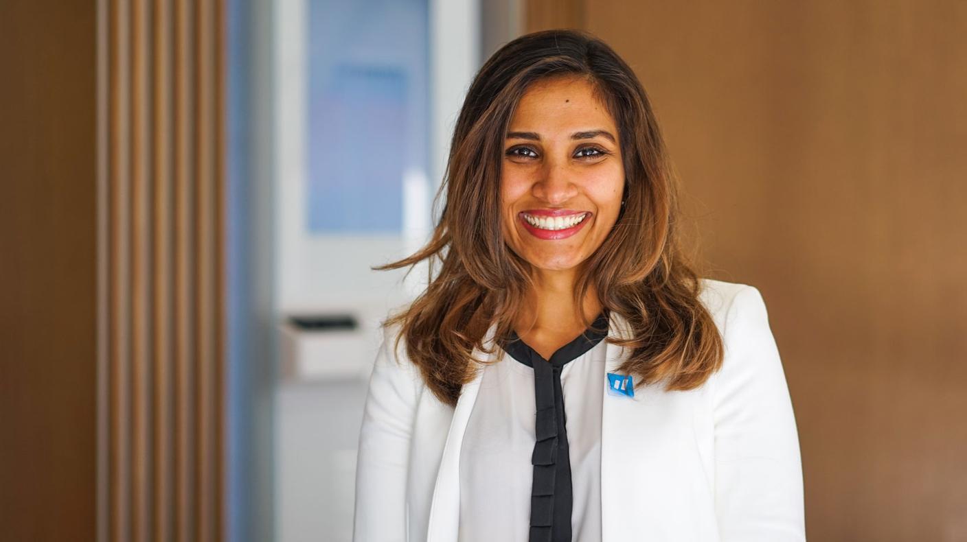 Forward doctor Pooja Singh standing in the foreground of a Forward location lobby.